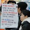 -18일 오후 서울역에서 한나라당의 날치기 예산을 규탄하는 팻말을 지나가는 시민들이 유심히 보고 있다.
