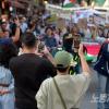 -4월 13일 오후 인사동길을 지나던 행인들이 팔레스타인 연대 30차 집회 행진 대열을 응원하며 휴대전화에 영상을 담고 있다. 